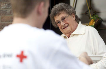 Foto: DRK-Mitarbeiter bringt Seniorin Essen